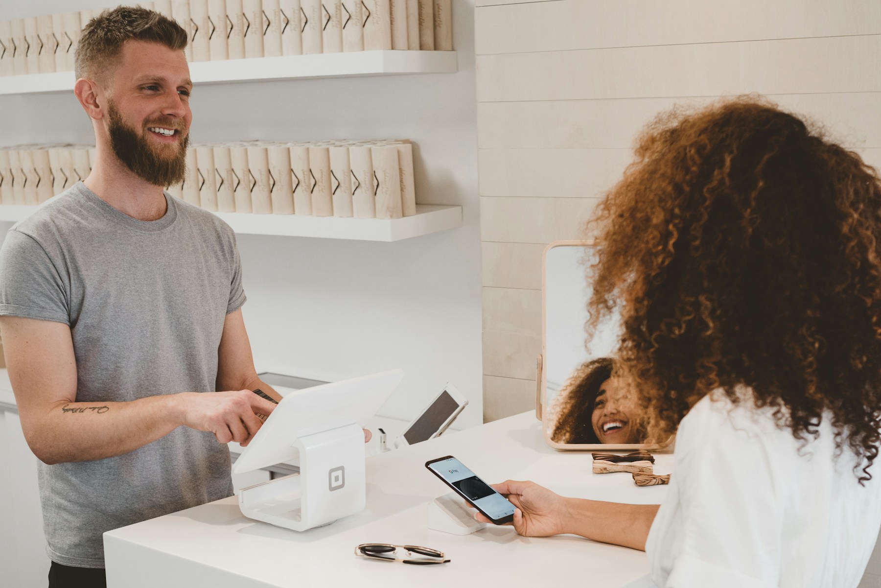 A shopkeeper assisting a customer at a retail checkout
